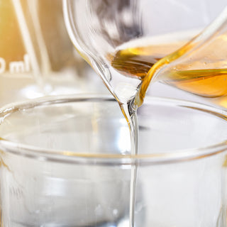 Cold process soap maker pouring essential oils into a measuring glass