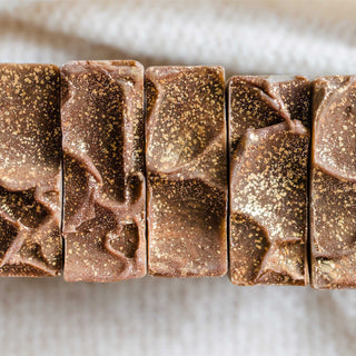 Top view of a loaf of Cozy Cocoa Butter Cashmere cold process soap bars on a cashmere blanket topped with gold sparkle